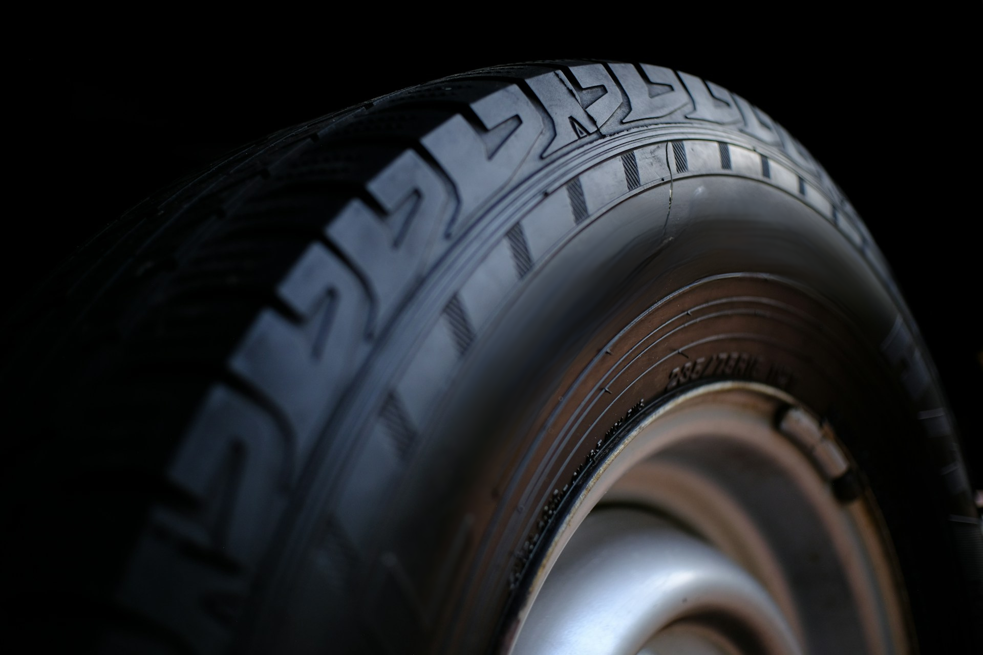 Close-up of a car tire with visible tread and a slight cut on the sidewall.