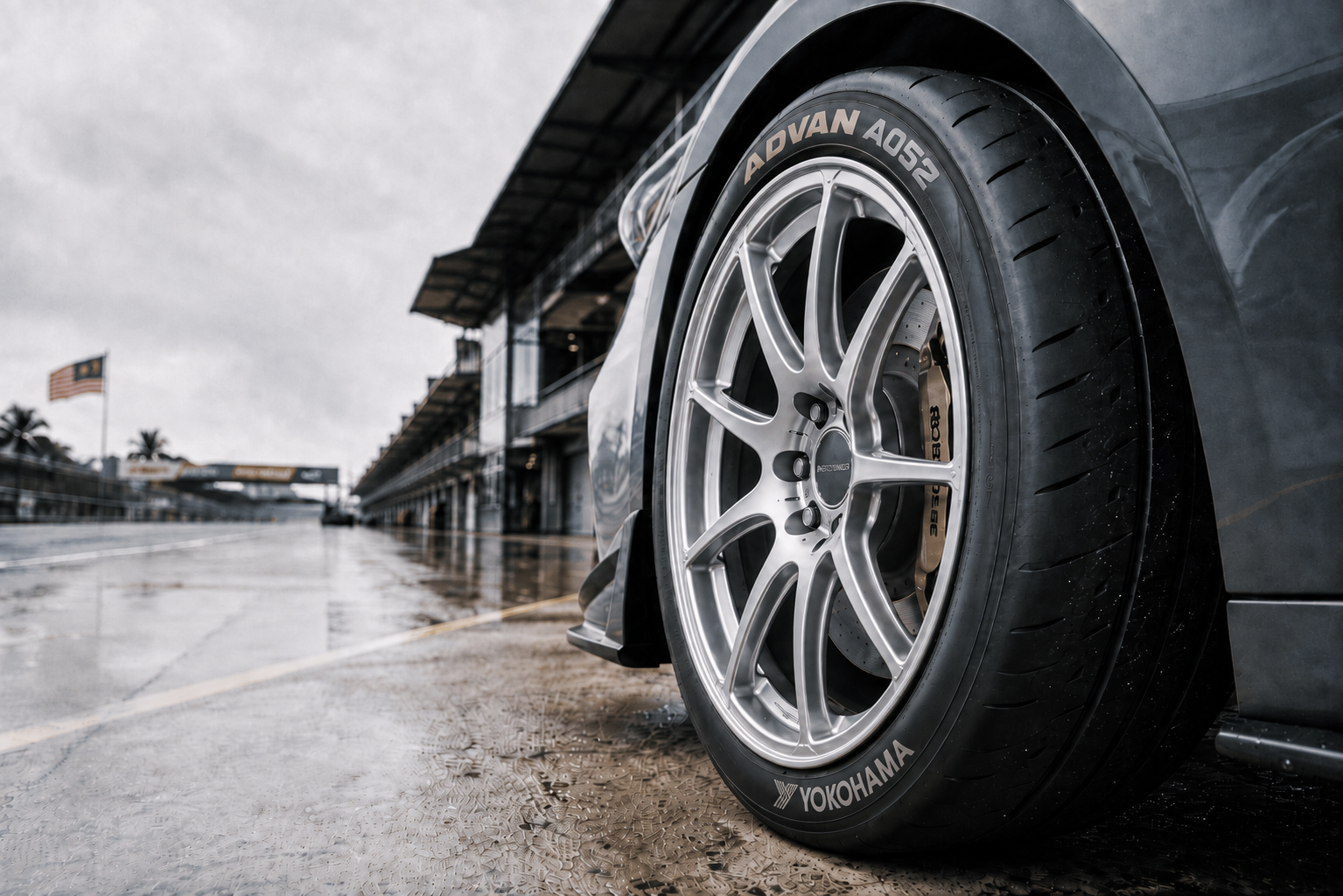 Close-up of a Yokohama ADVAN A052 semi-slick tyre fitted to a performance car at a wet racetrack in Malaysia