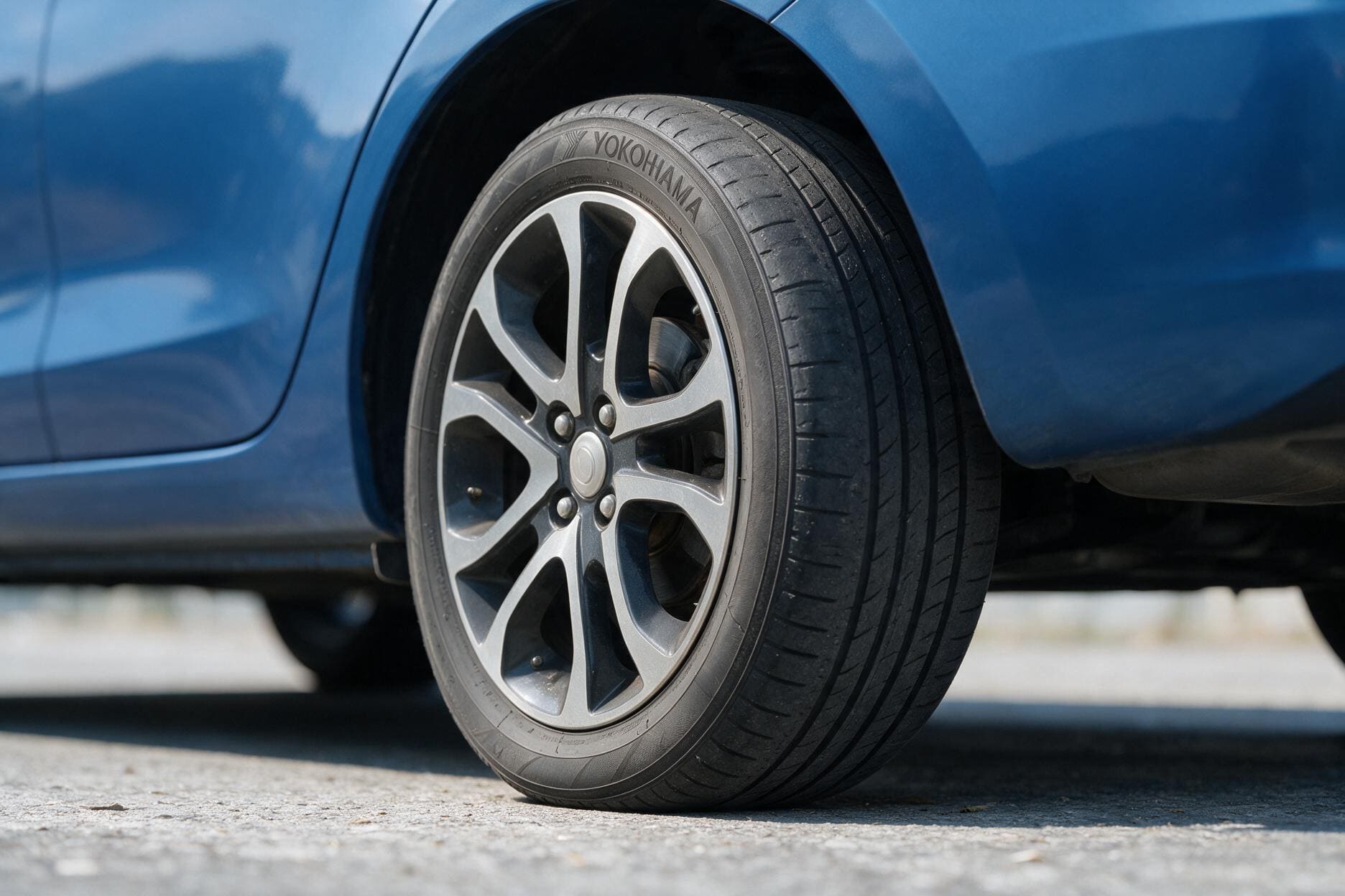 Tayar pada sebuah kereta biru menunjukkan corak bunga tayar yang semakin nipis.