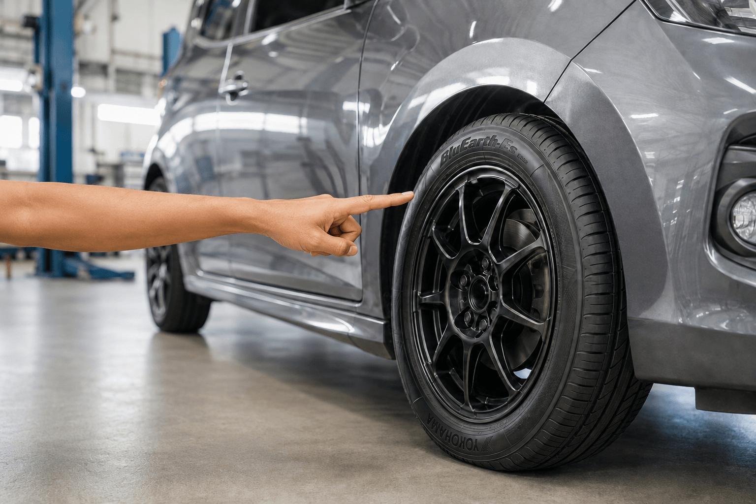 Hand inspecting the sidewall of a Yokohama BluEarth-Es ES32 tyre mounted on a Malaysian compact car.